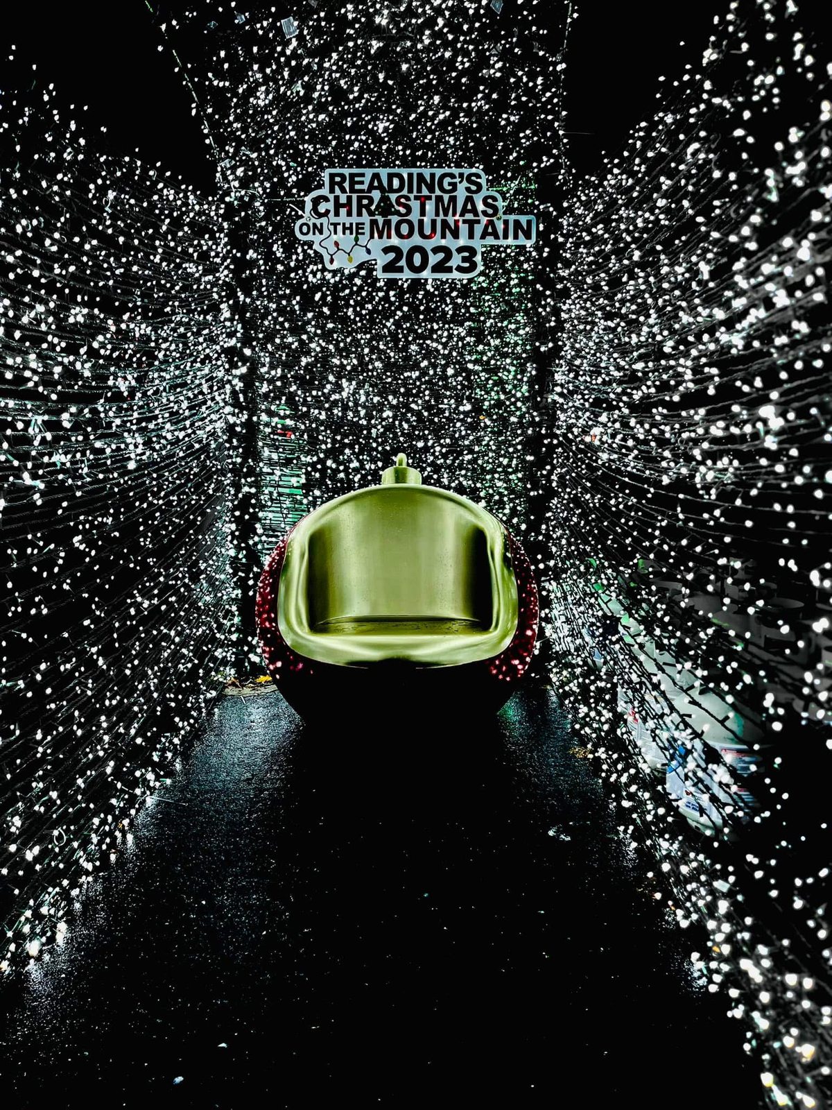 A seat inside a tunnel of white lights beneath a visible 2023 Christmas on the Mountain sign