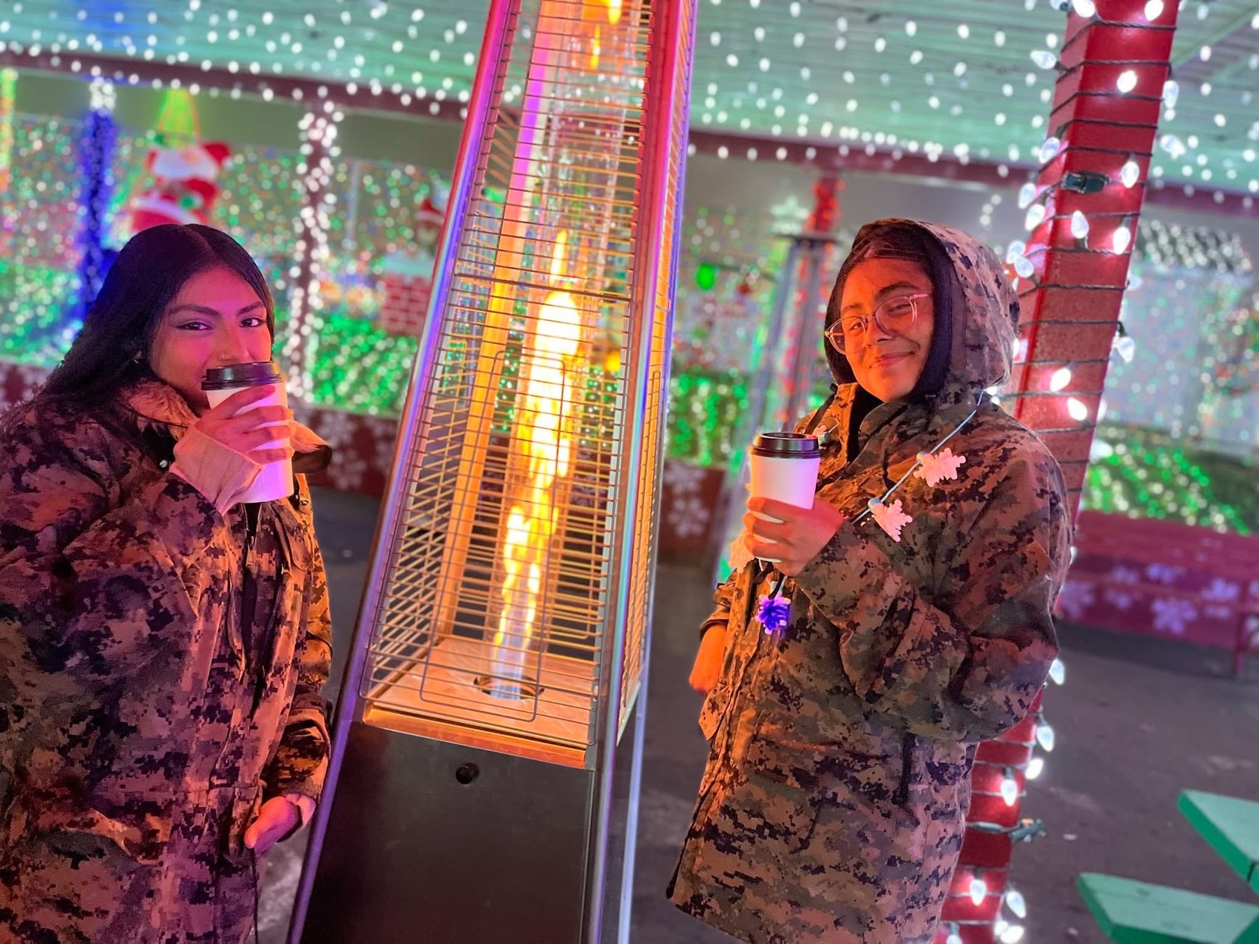 Two Marine Corps JROTC cadets warming up with hot drinks beside the display