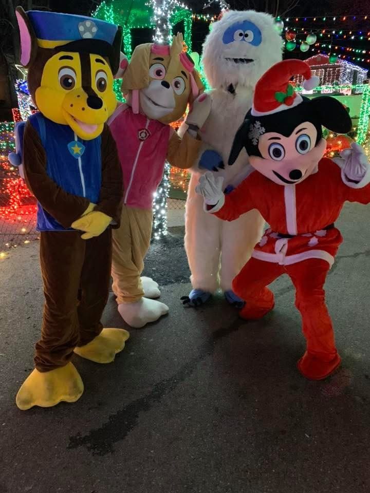 Costumed characters posing among Christmas lights